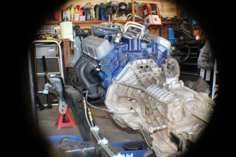 1968 Ford Bronco - Engine and transmission assembly on a stand in a garage workshop.