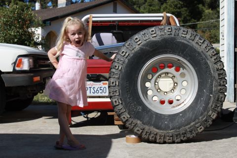 1968 Ford Bronco - A young girl poses next to a 1968 Ford Bronco, which is equipped with a large spare tire.