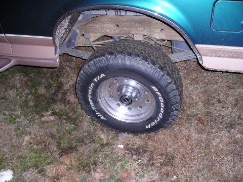 1996 Ford Bronco - The rear wheel and fender of a 1996 Ford Bronco, a teal and brown two-tone paint scheme.
