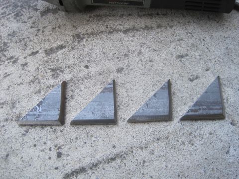 1989 Ford Bronco - Four metal brackets are laid out on a concrete surface next to a tool.