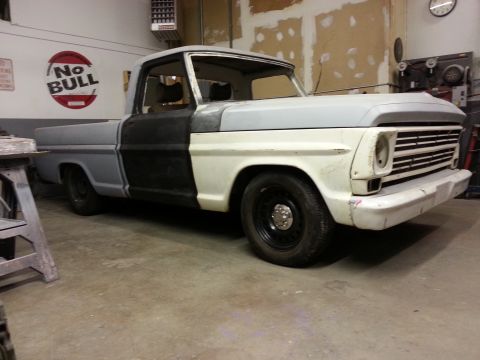 1967 Ford F-100 - This 1967 Ford F-100 truck is undergoing repairs in a garage, showing its front end and side.