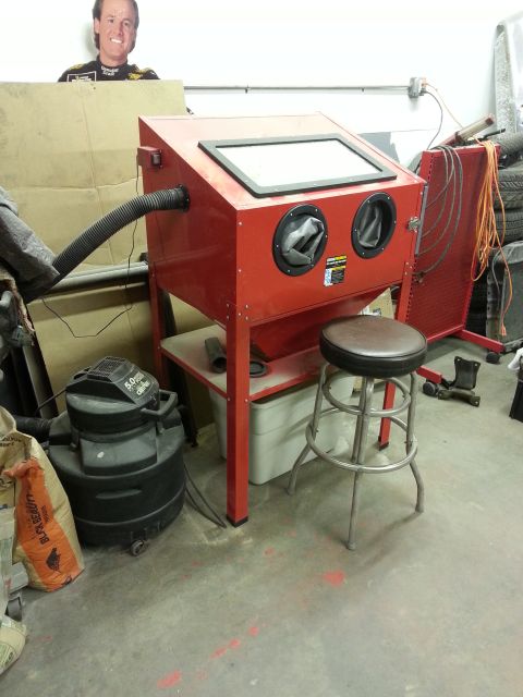 1967 Ford F-100 - A red sandblaster cabinet is in a garage with a stool and shop vac nearby.
