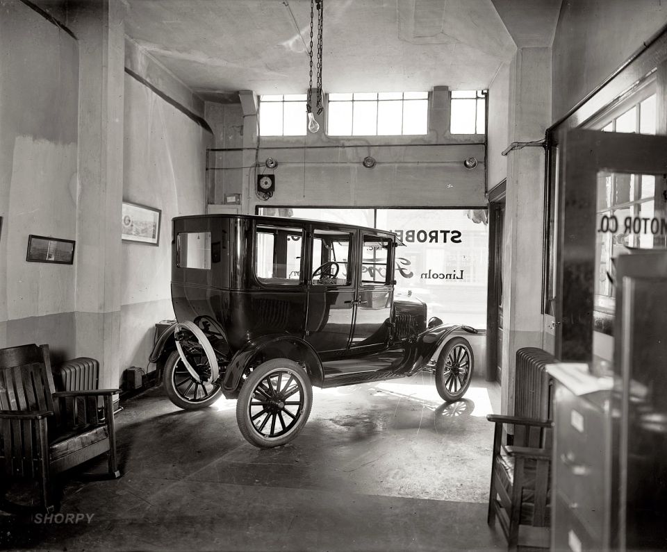 Dark sedan parked inside a garage, viewed from the front three-quarter angle