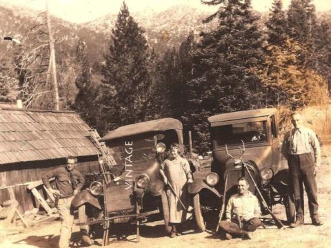 1909 Ford Model T - Two trucks and a group of people pose for a photo in a mountainous, wooded area.