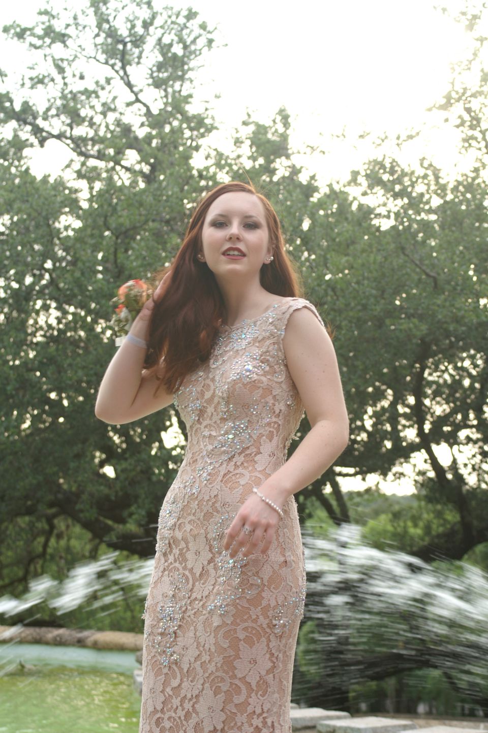 Woman in a formal dress posing by a fountain