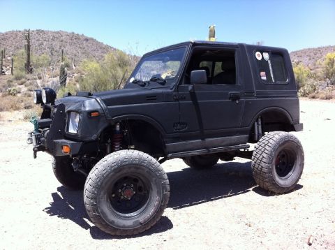 1987 Suzuki Samurai - A modified 1987 Suzuki Samurai with off-road tires and a custom bumper sits in a dry, desert environment.