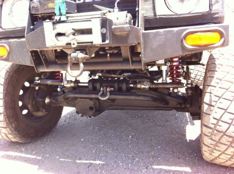 1987 Suzuki Samurai - Close-up of the front axle and suspension system of a Suzuki Samurai, including a winch.