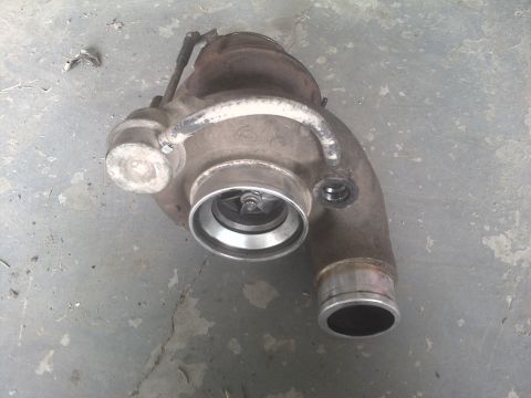 2005 Dodge 3500 - A turbocharger unit is shown resting on a concrete surface, with its internal components visible.