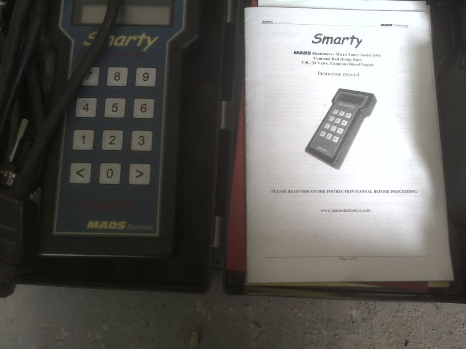 Smarty diagnostic tool with keypad and screen, next to its instruction manual detailing its use for Common Rail Dodge Ram 5.9L engines