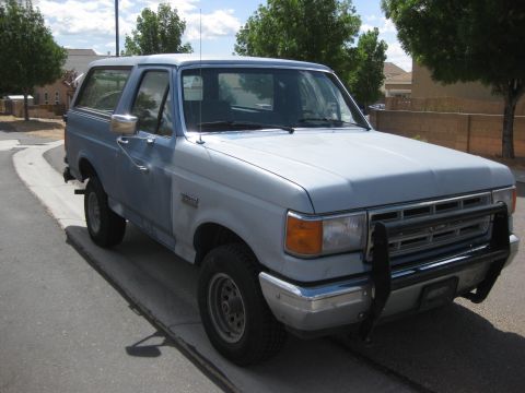 1988 Ford Bronco - This 1987 Ford Bronco is seen from a three-quarter front view, a prominent black bull bar on its front grille.
