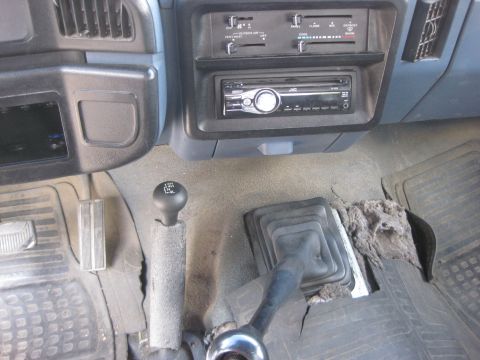 1988 Ford Bronco - The interior of a truck shows the dashboard, radio, and two gear shifters, indicating a manual transmission and four-wheel drive capability.