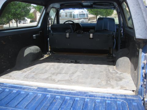 1988 Ford Bronco - The interior of a blue SUV shows its cargo area and rear seats, with an Airstream trailer visible outside.