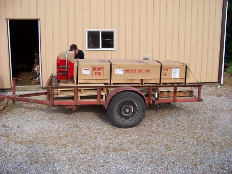 1995 Mercury Grand Marquis - A trailer carries several large boxes labeled 'Rotary Lift' and 'Heavy End' in front of a building.