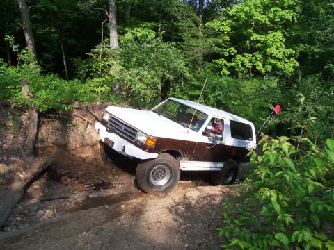 1989 Ford Bronco - A white and brown Ford Bronco navigates a challenging off-road trail.
