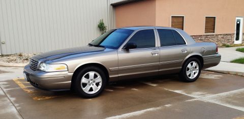 2005 Ford Crown Victoria - A 2005 Ford Crown Victoria sedan is parked outside a building.