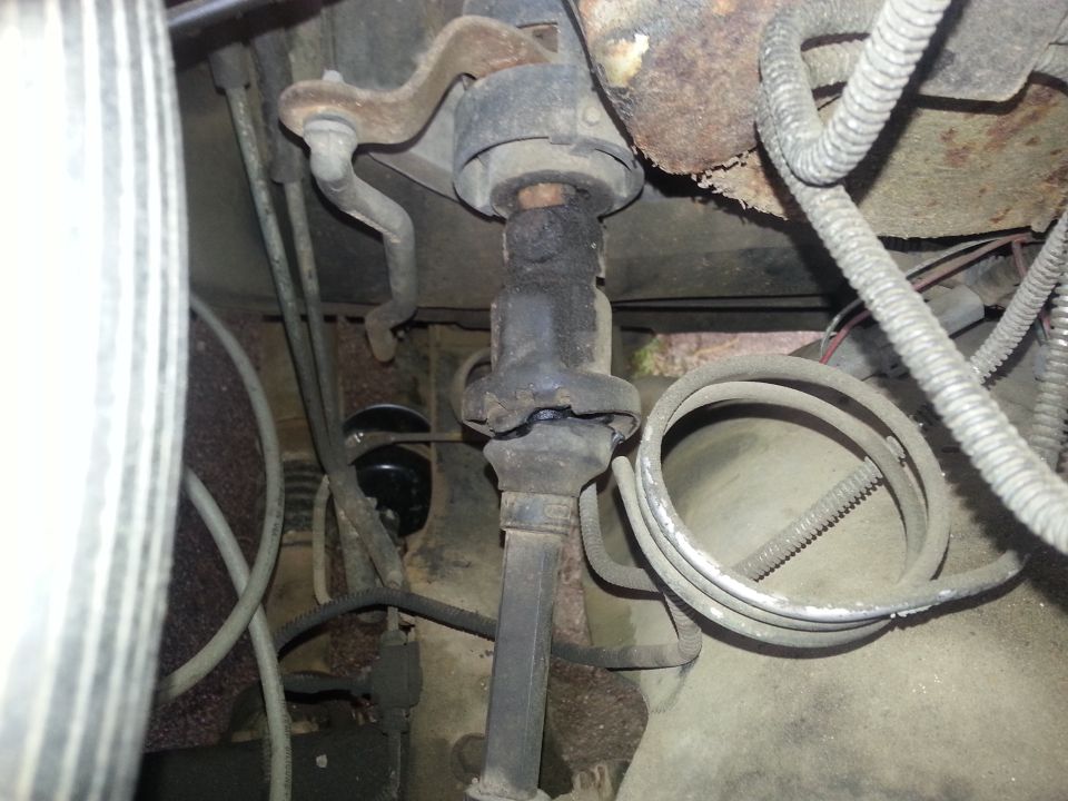 Steering column and engine bay components with visible wiring and hoses. Some rust present