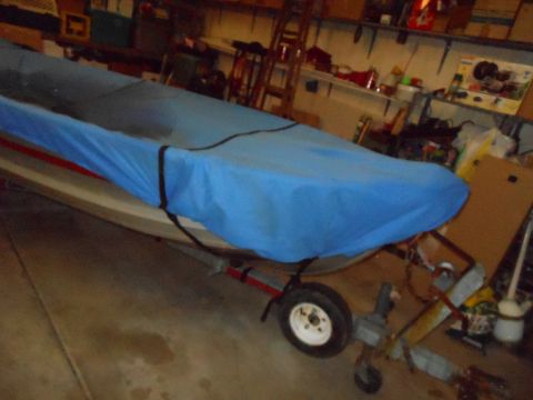 1996 Ford F-150 - A boat covered by a blue tarp is parked on a trailer inside a garage.