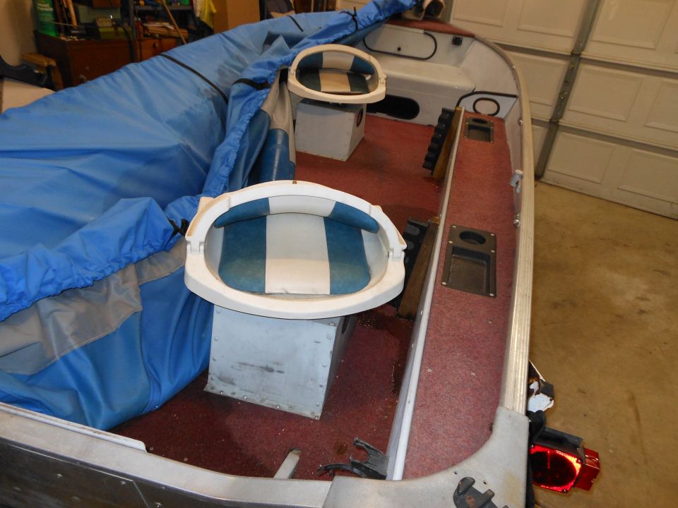 Boat interior with blue cover, two seats, and red carpet
