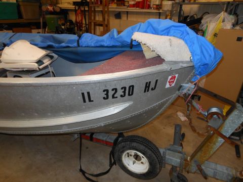 1996 Ford F-150 - An aluminum boat is partially covered by a blue tarp while on a trailer in a garage.