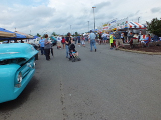 2013 Ford F-100 - Outdoor car show with spectators and vendor tents under a cloudy sky.