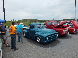 2013 Ford F-100 - Several classic Ford pickup trucks are displayed at an outdoor event under a cloudy sky.