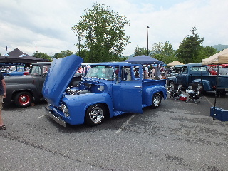 2013 Ford F-100 - A blue pickup truck is displayed with its hood and door open at an outdoor event.