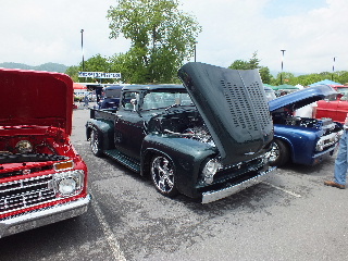 2013 Ford F-100 - Several classic pickup trucks are displayed with their hoods open at an outdoor event.