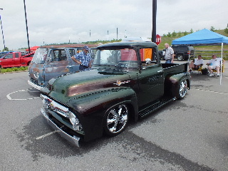 2013 Ford F-100 - A classic 1956 Ford F-series pickup truck is displayed at a car show, with other vehicles and tents in the background.