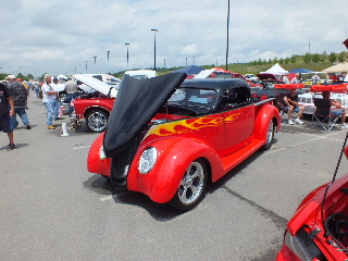 2013 Ford F-100 - A custom hot rod with a black top and flame decals is displayed with its hood open at a car show.