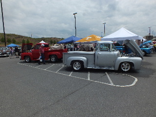 2013 Ford F-100 - Two classic pickup trucks, a silver Ford and a red one, are displayed at an outdoor event.