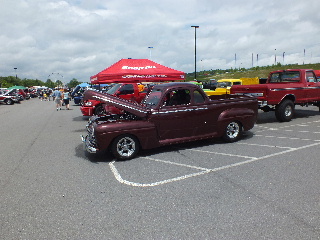 2013 Ford F-100 - A classic maroon pickup truck is displayed at an outdoor event, with its hood open for viewing.