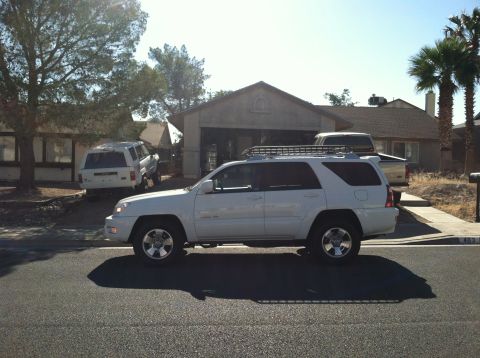 2003 Toyota 4Runner - A white 2003 Toyota 4Runner is parked in front of a house with a garage and another SUV in the background.
