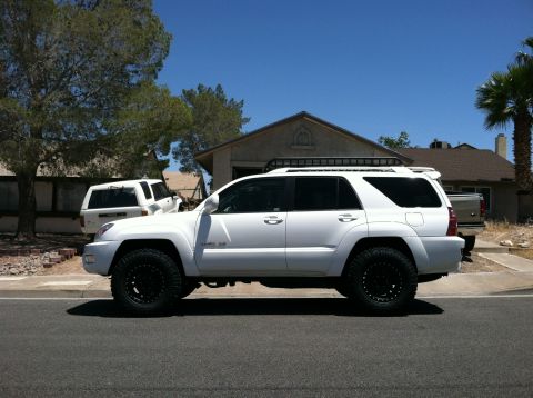 2003 Toyota 4Runner - A white 2003 Toyota 4Runner is parked on the street with a roof rack and off-road tires.