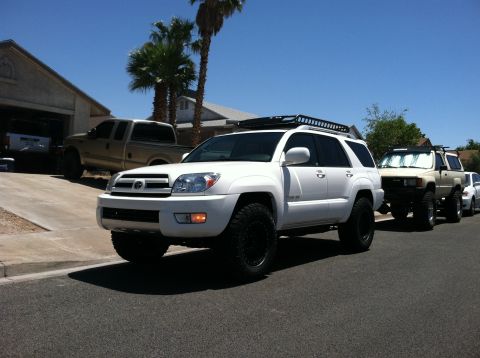 2003 Toyota 4Runner - A white 2003 Toyota 4Runner is parked on the street with other vehicles behind it.