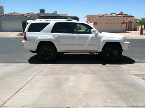 2003 Toyota 4Runner - Side view of a white 2003 Toyota 4Runner equipped with a roof rack and off-road tires.