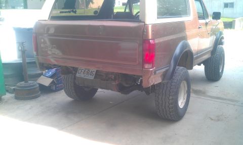 1987 Ford Bronco - The rear of a brown Ford Bronco is shown, missing its bumper and with a visible license plate.