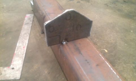 1987 Ford Bronco - A metal bracket with handwritten markings is welded onto a steel beam, possibly a component for a vehicle's rear bumper.