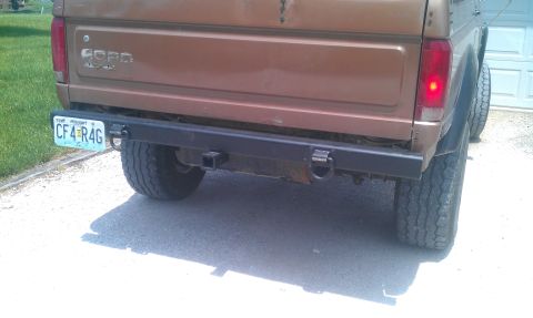 1987 Ford Bronco - The rear of a brown Ford Bronco is shown with a custom bumper and a license plate.