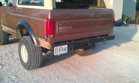1987 Ford Bronco - The rear of a brown Ford Bronco is visible, large tires and a black bumper.