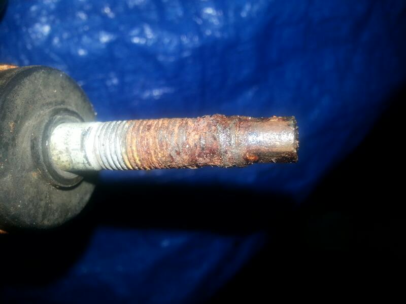 Close-up of a heavily rusted bolt with visible threads and a rubber grommet