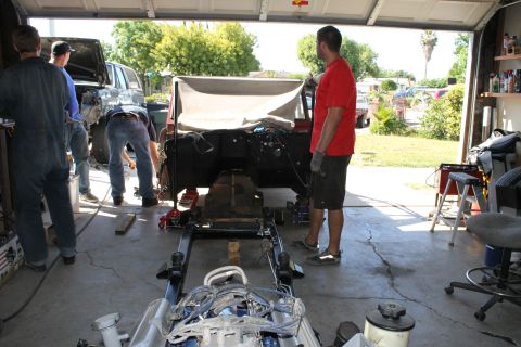 1968 Ford Bronco - A 1968 Ford Bronco is shown in a garage with its chassis and drivetrain exposed, indicating ongoing mechanical work.