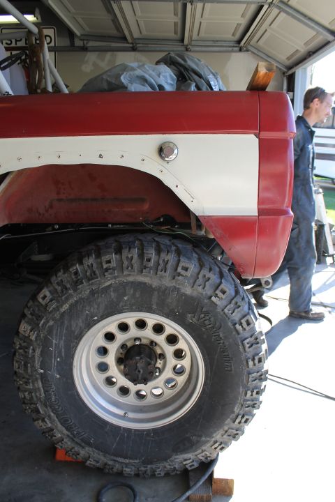 1968 Ford Bronco - The rear section of a classic Ford Bronco is shown with a large tire and a person in the background.
