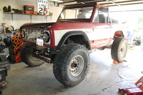 1968 Ford Bronco - This 1968 Ford Bronco, painted red and white, sits in a garage with oversized tires.