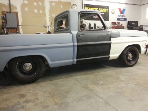 1967 Ford F-100 - Side view of a 1967 Ford F-100 pickup truck in a workshop, showing different paint stages.