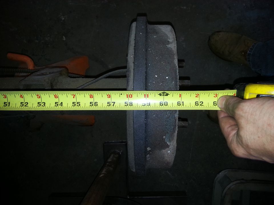 Measuring a brake drum with a yellow tape measure. The drum is approximately 12 inches in diameter
