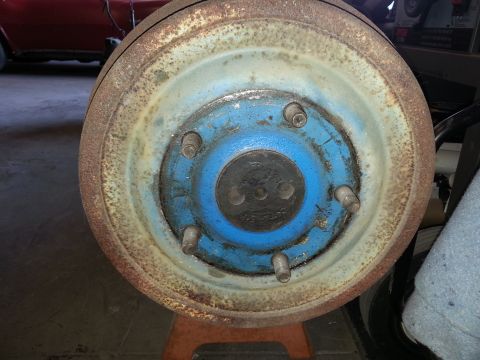 1967 Ford F-100 - This is a close-up of a rusty brake drum, likely from an older vehicle, resting on an orange jack stand.