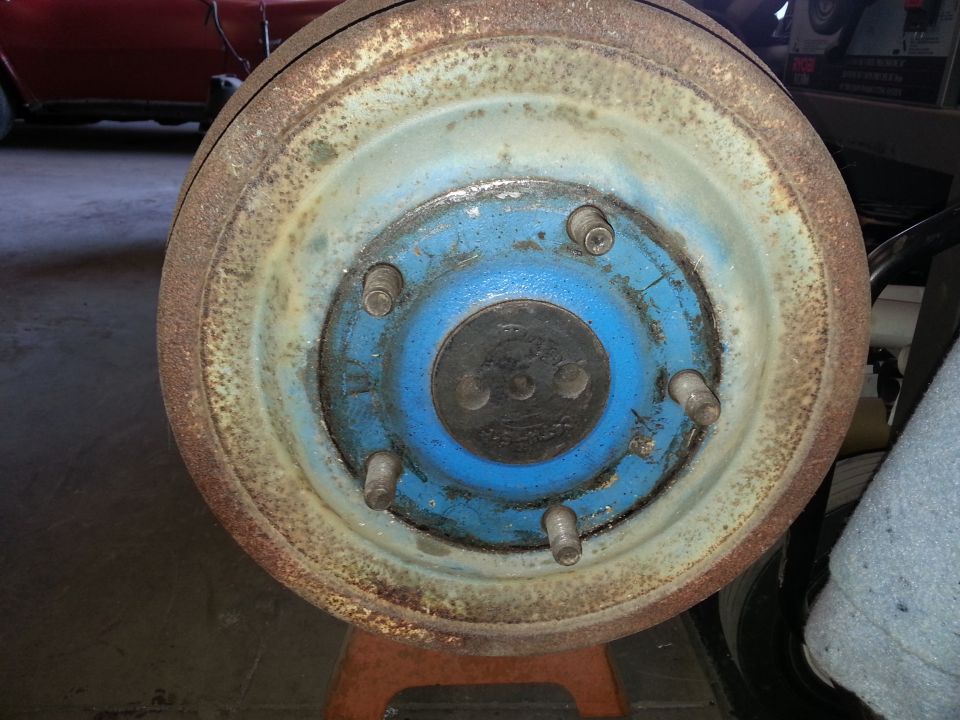 Close-up of a rusty vehicle brake drum with a blue hub