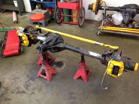 1988 Ford Bronco - Front axle assembly with yellow brake calipers and a yellow steering stabilizer is shown on jack stands.