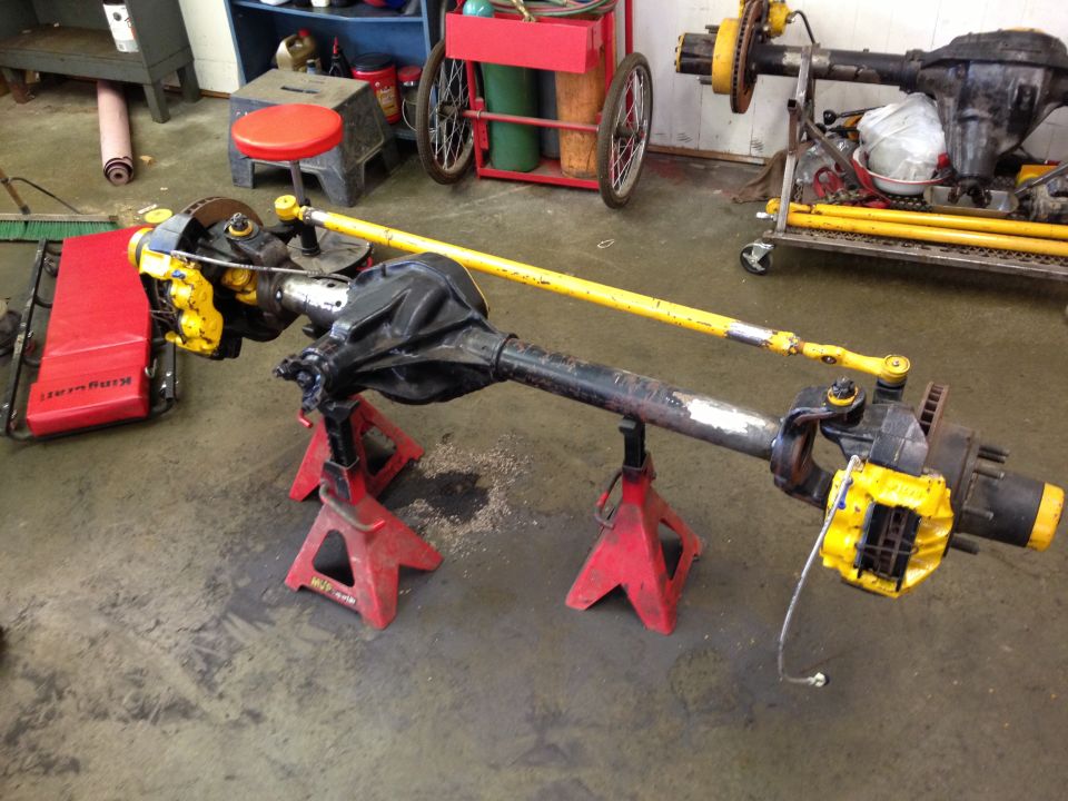 Front axle assembly with yellow brake calipers on red jack stands