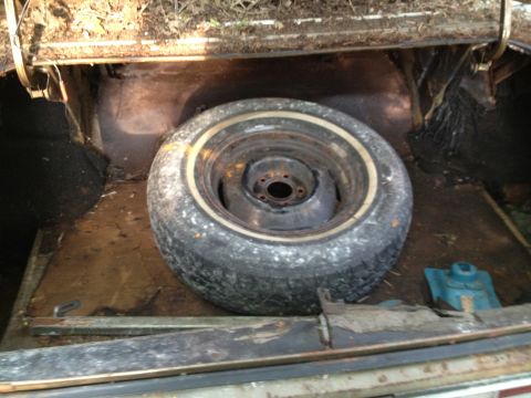 1988 Ford Bronco - The spare tire sits in the dusty trunk of a vehicle, showing signs of age and disuse.